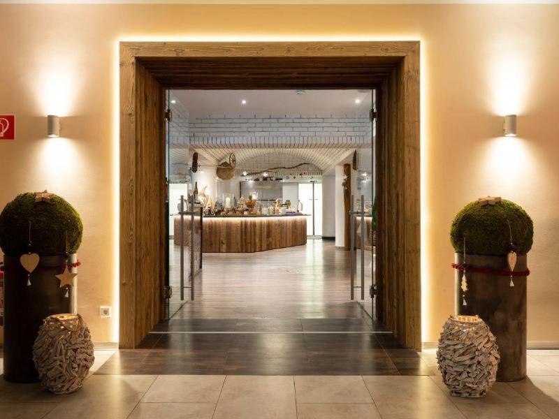 Entrada elegante del hotel con marco iluminado, dos plantas y vista de la recepción al fondo