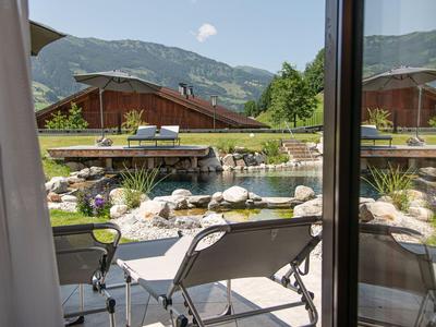 Vista da una camera su due lettini e un giardino con stagno e montagne sullo sfondo.