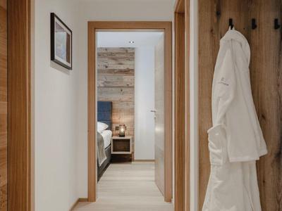 Moderno pasillo de hotel con pisos de madera clara y batas colgadas en la pared.