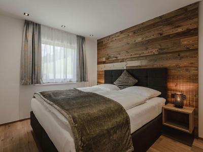 Acogedor dormitorio con pared de madera, cama doble y mesita de noche con lámpara.