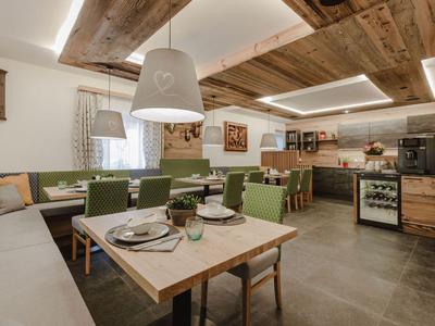 Zona pranzo moderna con tavolo in legno, sedie verdi e soffitto con travi in legno rustico.