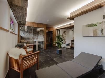 Habitación moderna y acogedora con toques de madera y piedra, asientos y plantas.