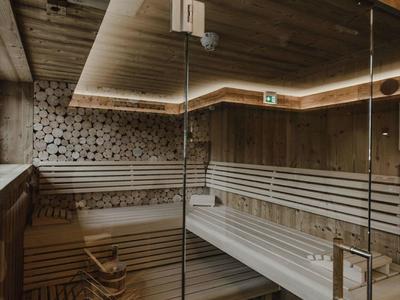 Moderna sala de sauna con paredes de madera y mampara de vidrio con luz cálida.
