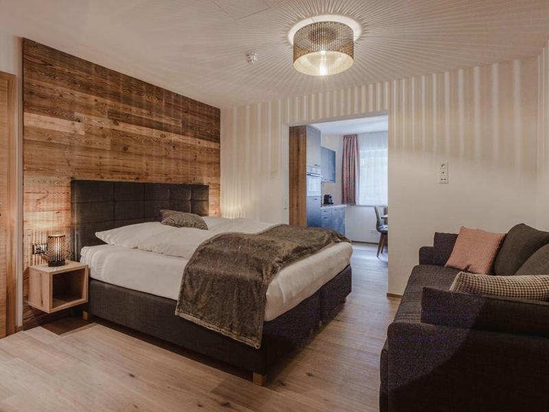 Acogedora habitación de hotel con cama doble, pared de madera, sofá y luz tenue.