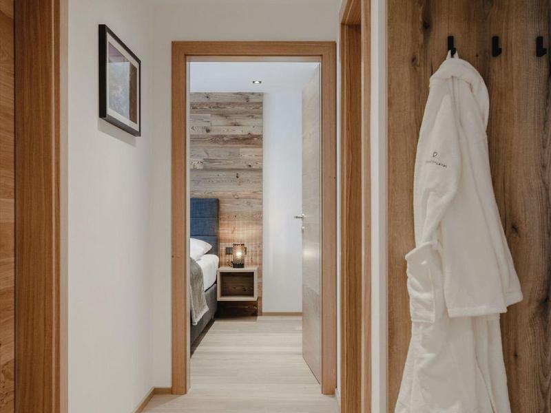 Moderno pasillo de hotel con pisos de madera clara y batas colgadas en la pared.