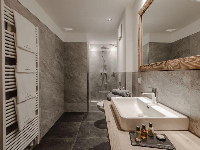 Baño moderno con lavabos claros, grandes espejos y ducha sin mampara.