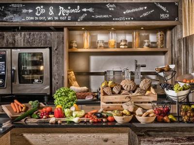 Verdure fresche, pane e prodotti da forno su un buffet rustico con forno sullo sfondo.