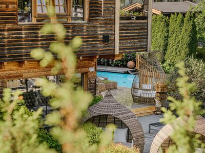 Área exterior con arquitectura de madera, piscina y asientos cómodos rodeados de vegetación.