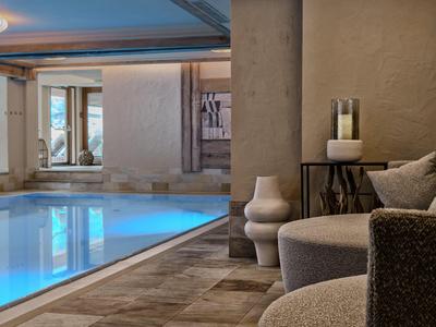 Piscina interior moderna con asientos cómodos y luz suave en un hotel.