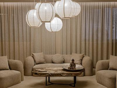 Cómodo salón de hotel con mesa de centro redonda de madera y faroles de papel modernos.