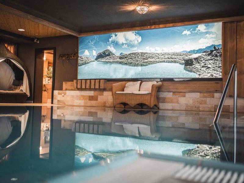 Piscina interna con pareti in legno e grande dipinto paesaggistico sotto luce calda