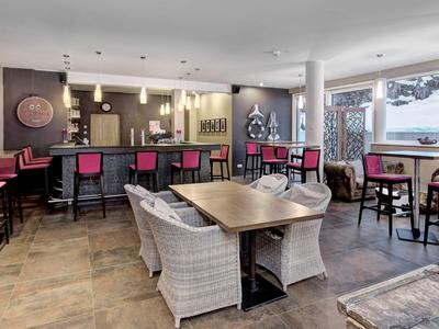 Moderner Hotelbarbereich mit Sitzgelegenheiten, Holztischen und großen Fenstern