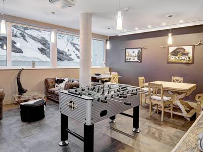 Gemütlicher Aufenthaltsraum mit Tischkicker, Sitzbereich und großen Fenstern mit Bergblick.