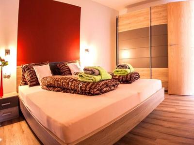 Modernes Schlafzimmer mit großem Bett, rotbraunem Kopfteil und Holzschrank.