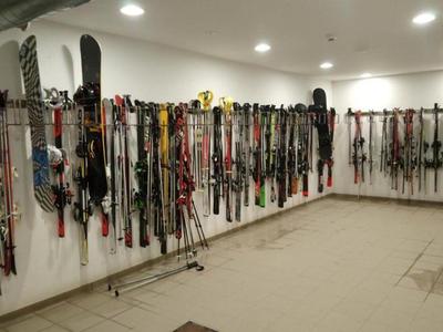 Großer Raum mit vielen an der Wand hängenden Skiern und Skistöcken.