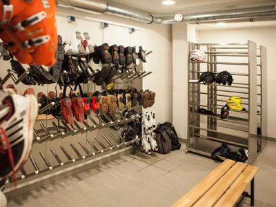 Ein Raum mit Wandregalen, die Wintersportausrüstung wie Skischuhe und Helme tragen.