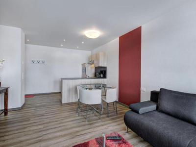 Moderner Wohnbereich mit Sofa, Stühlen, roter Wand und offener Küche mit Theke.