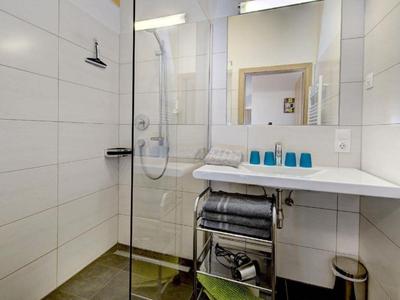 Modernes Badezimmer mit bodengleicher Dusche, großem Spiegel und Waschtisch mit Handtüchern