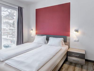 Bedroom with double bed, red wall panel, and view of snowy landscape.