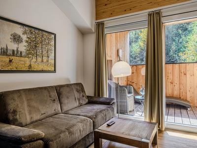 Cozy living room with brown sofa, wooden table, and access to terrace with wooden panels.