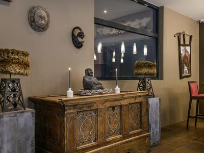 A cozy hotel area with wooden sideboard, decorative lamps, and candles.