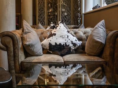 Cozy brown leather sofa with pillows in a warm, elegant room.