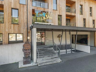 Entrance to a hotel with wooden facade, stairs, and a sculpture of a human head.