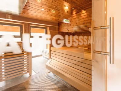 Moderner Saunaraum mit Holzverkleidung und Sitzbänken in heller Farbstimmung.