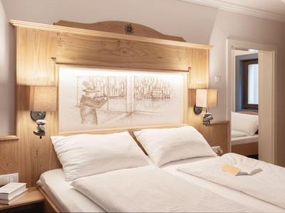 Elegantes Hotelzimmer mit Doppelbett, Holzwand und weicher Beleuchtung.