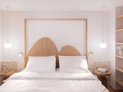 Schlichtes Doppelbett mit runden Holzkopfteil und weißen Bettwäsche in modernem Hotelzimmer.