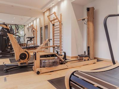 Moderner Fitnessraum mit Holz-Trainingsgeräten und großen Spiegeln in einem Hotel.