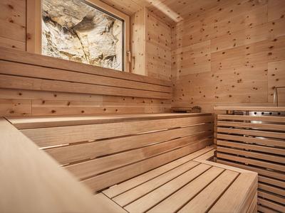 Saunaraum mit Holzbänken und einem Fenster mit Blick auf Felsen.