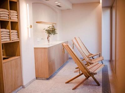 Heller Wellnessbereich mit Holzstühlen und Regalen voller weißer Handtücher.