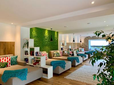 Habitación de hotel moderna con varias camas, pared verde y decoración acogedora.