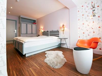 Habitación de hotel moderna con cama doble, suelo de madera y papel pintado colorido y brillante.