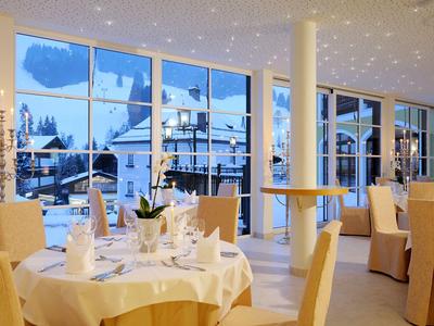 Elegante área de comedor de hotel con mesas puestas y vista a montañas nevadas.