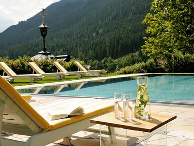 Área de piscina relajante con tumbonas y montañas al fondo.