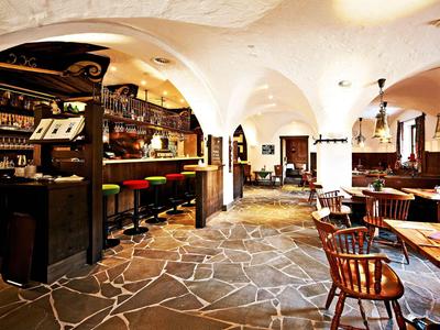 Luminoso comedor de hotel con suelo de piedra, muebles de madera y barra bajo techo abovedado.