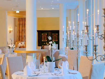 Restaurante elegante con mesas vestidas de blanco y candelabros plateados en ambiente luminoso.