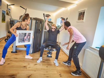 Tres personas hacen ejercicio y se motivan en el gimnasio moderno de un hotel.