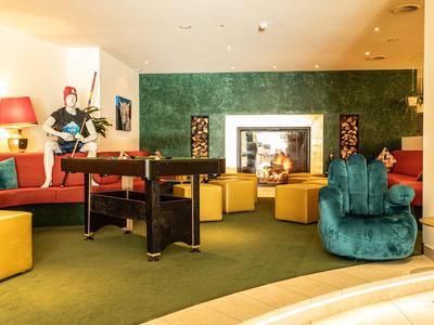 Zona lounge de hotel elegantemente decorada con varios asientos y una chimenea.