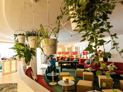Zona lounge moderna con asientos coloridos y plantas colgantes.