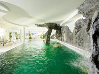 Piscina cubierta moderna con rocas y techo blanco en un hotel.