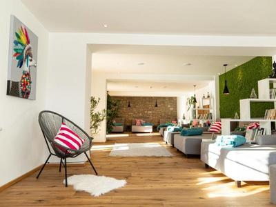 Sala de estar luminosa con suelo de madera, muebles modernos y áreas de descanso acogedoras.