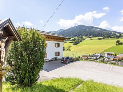Ländliche Hotelumgebung mit weißen Gebäuden, bewaldeten Bergen und blauem Himmel im Hintergrund.
