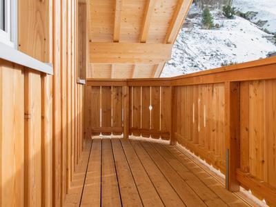 Balkon mit Holzverkleidung und Geländer, Blick auf schneebedeckte Landschaft.