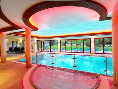 Modernes Hallenbad mit beleuchtetem Whirlpool und Panoramafenstern zum Garten.