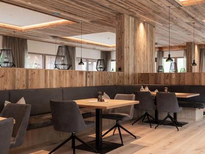 Modern restaurant with wood accents, upholstered chairs, and large windows.