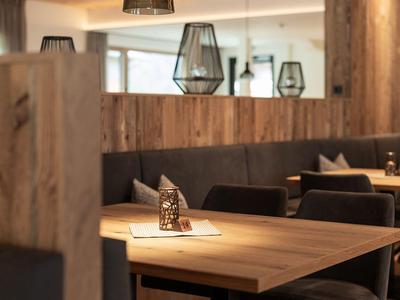 Modern hotel dining area with wooden tables, padded benches, and stylish lamps.