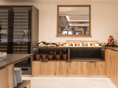 Modern kitchen with wooden furniture, buffet, and wine cooler in a hotel.